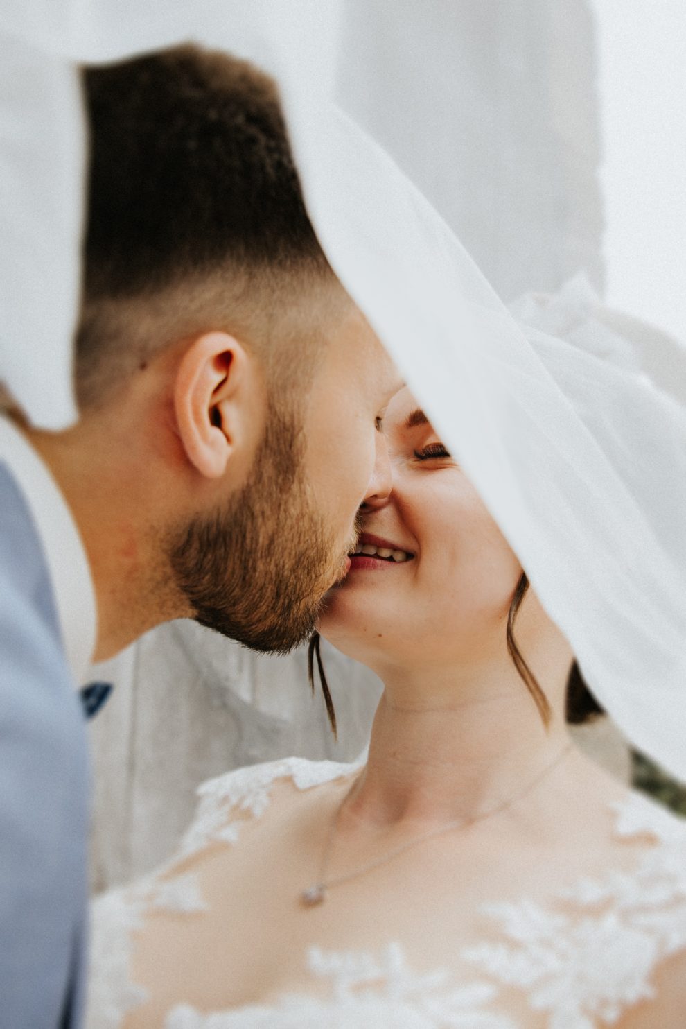 Hochzeit in Schloss Berlepsch: Bräutigam küsst die Braut zärtlich unter ihrem Schleier.
