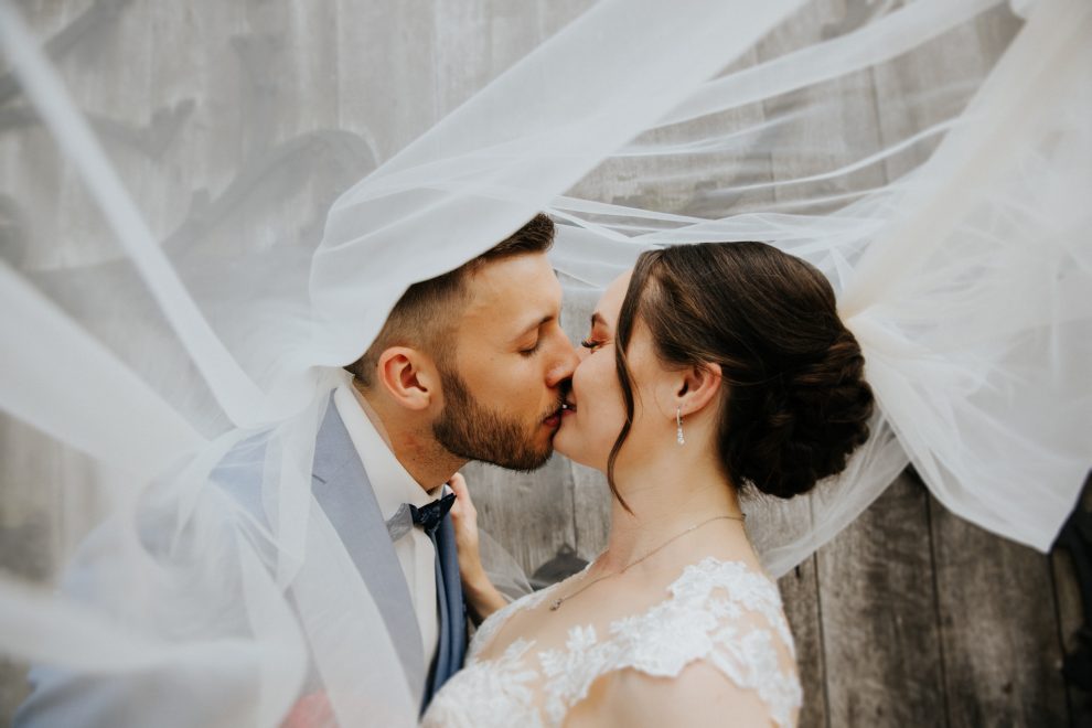 Romantischer Moment: Bräutigam und Braut teilen einen Kuss unter ihrem Schleier.